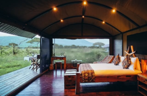 Interior of a best luxury safari lodge featuring a spacious bedroom with panoramic views of the African wilderness and elegant wooden décor